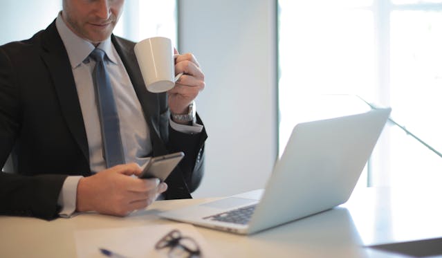 A Man In Black Suit Drinking Coffee During Daylight