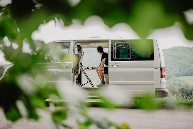 A Person Sitting Inside a Van in front of His Laptop while Looking Afar.jpg