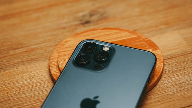 Detailed-close-up-of-a-modern-smartphone-camera-on-a-textured-wooden-surface