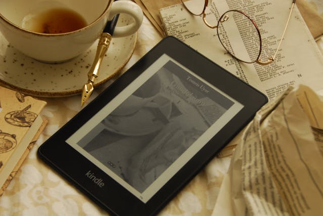 Kindle bralnik ob skodelici kave