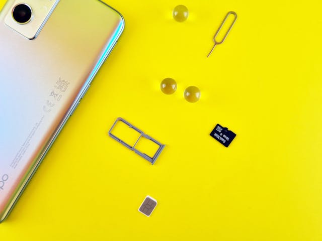mobilni telefon s SIM kartico in spominska kartica na rumeni podlagi.jpg